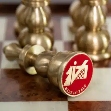 Detalle de un peón de latón caído sobre el tablero, medallón rojo grabado