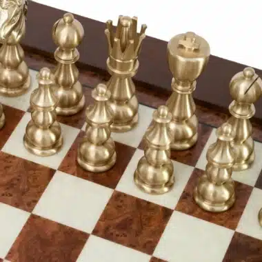 Piezas de ajedrez de latón dorado dispuestas sobre el tablero de madera con marquetería