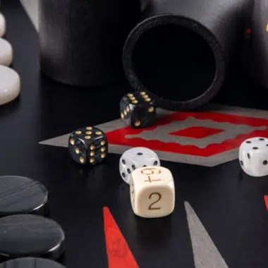 Backgammon de madera de roble negro y plateado, dados y cubilete sobre el tablero