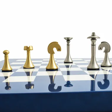 Piezas de latón dorado y plateado alineadas sobre el tablero azul