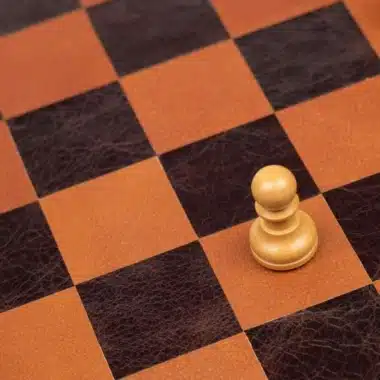 Peón de madera clara aislado sobre el tablero de cuero marrón y naranja
