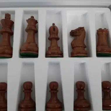 Piezas oscuras del juego Staunton Printemps alineadas en su caja, primer plano