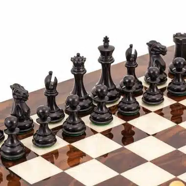 Piezas de ajedrez negras de ébano alineadas sobre el tablero de brezo