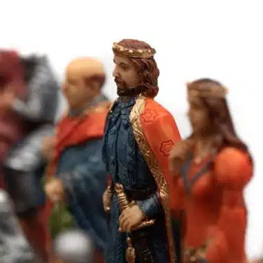 Pieza rey con capa roja y corona dorada entre las figuras medievales