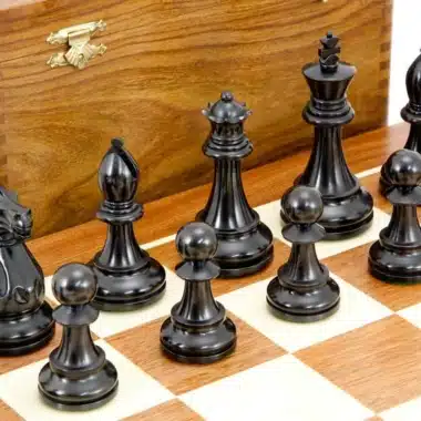 Detalle de las piezas negras talladas, rey, dama y peones, sobre el tablero de madera