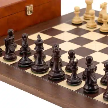Piezas negras y blancas dispuestas sobre el tablero de ajedrez en madera dorada
