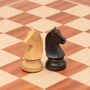 Caballos claro y oscuro colocados uno junto al otro sobre el tablero de caoba