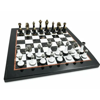 Juego de ajedrez completo sobre tablero de mármol blanco y negro, piezas doradas y plateadas