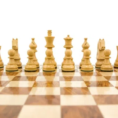 Piezas blancas del juego de ajedrez Staunton alineadas sobre el tablero de madera