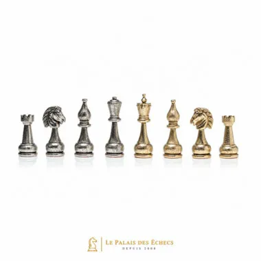 Piezas de ajedrez de metal plateado y dorado alineadas sobre fondo blanco