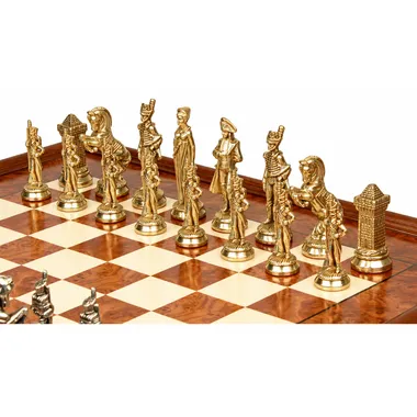 Piezas doradas del juego de ajedrez Napoleón alineadas sobre el tablero de madera de olmo