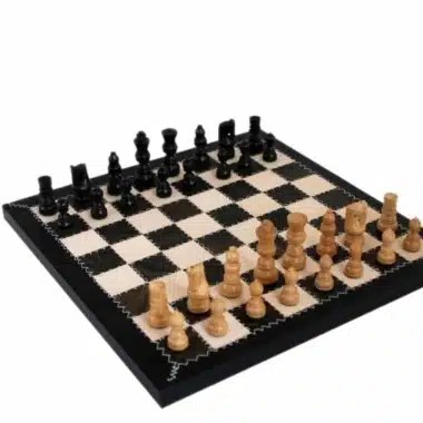 Juego de ajedrez en madera clara y negra sobre tablero de cuero auténtico