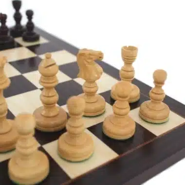 Piezas claras de madera clara colocadas en el tablero, caballo y alfil en primer plano