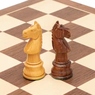 Caballos claro y oscuro frente a frente sobre el tablero de nogal y arce