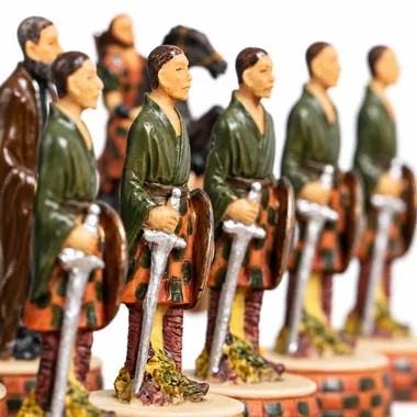 Piezas de ajedrez en fila que representan guerreros escoceses con kilt armados de espadas