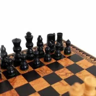 Detalle de las piezas negras de madera alineadas en el tablero de símil cuero