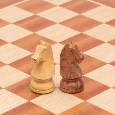 Caballos de madera de rosa y boj colocados uno junto al otro sobre el tablero de caoba