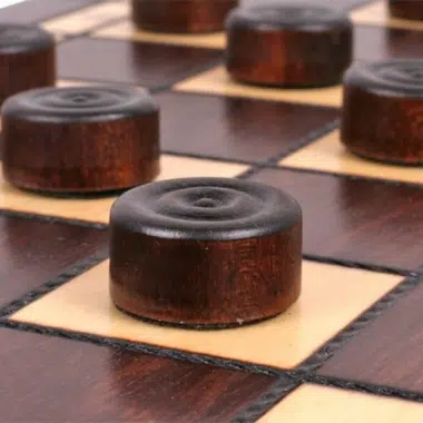 Juego de damas de madera, fichas oscuras colocadas en las casillas claras del tablero