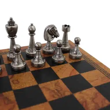 Piezas plateadas Staunton de metal en primer plano sobre tablero de símil cuero con mapa antiguo