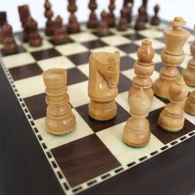 Detalle de las piezas claras, caballo y alfil, sobre el tablero con marquetería