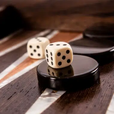 Fichas negras y dados blancos colocados sobre el tablero con motivos en nácar