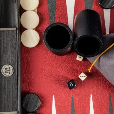 Cubiletes de dados negros, dados y fichas sobre el tablero rojo burdeos