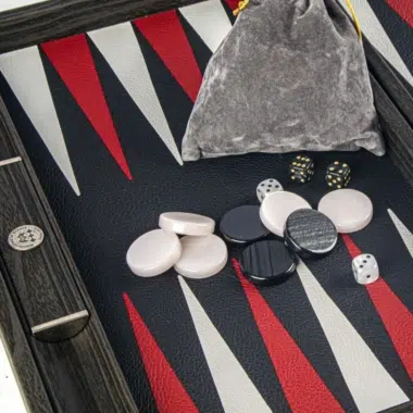 Detalle de las fichas, dados y bolsa de terciopelo gris sobre el tablero de backgammon