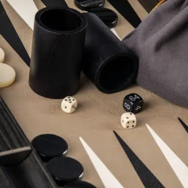 Cubiletes de dados de madera y bolsa de tela sobre el tablero de backgammon