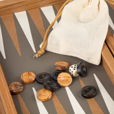 Fichas de backgammon de madera y dados sobre el tablero con bolsa de tela