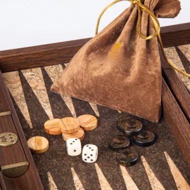 Fichas de madera de olivo, dados y bolsa de terciopelo sobre el tablero de corcho