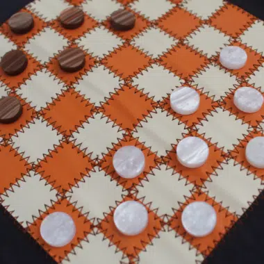 Superficie del juego de damas sobre tapete flexible naranja y crema con fichas marmoladas